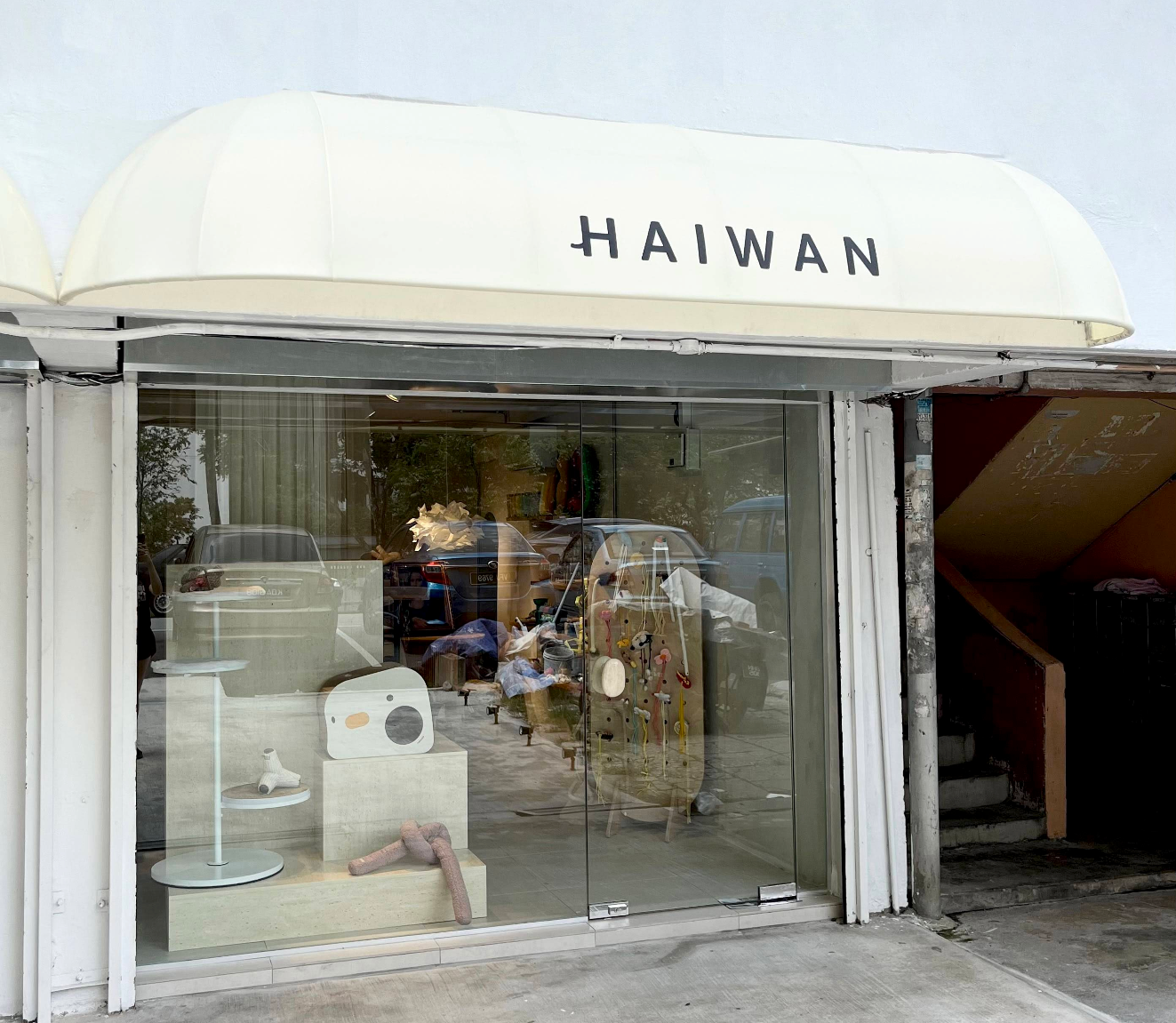 Storefront with glass window displaying various items and a white canopy with 'HAIWAN' branding.